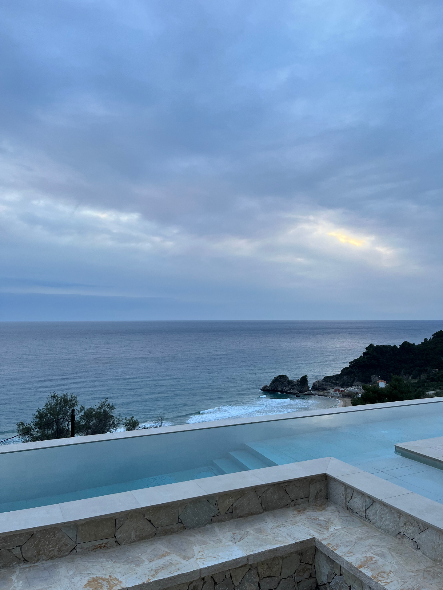 Infinity pool above a wild Corfu cove at dusk